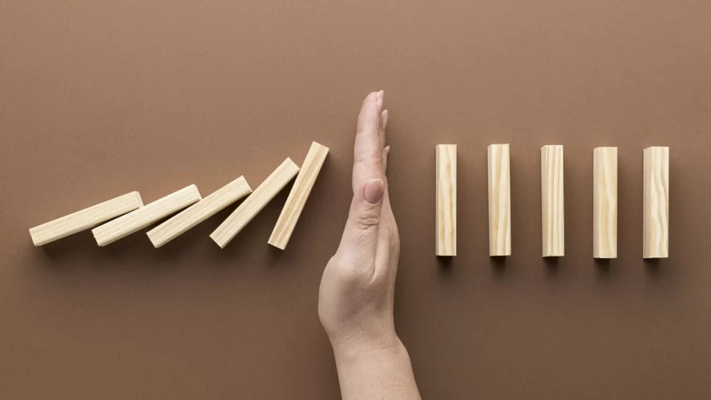 Hand stopping falling wooden blocks — concept of avoiding common SEO mistakes in meta descriptions