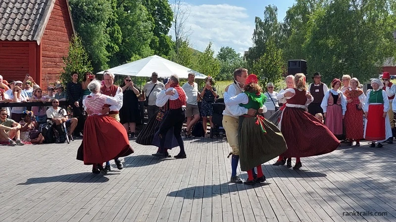 Couples dancing in traditional Swedish costumes during a Midsummer festival, used as an example of alt text for travel photos.