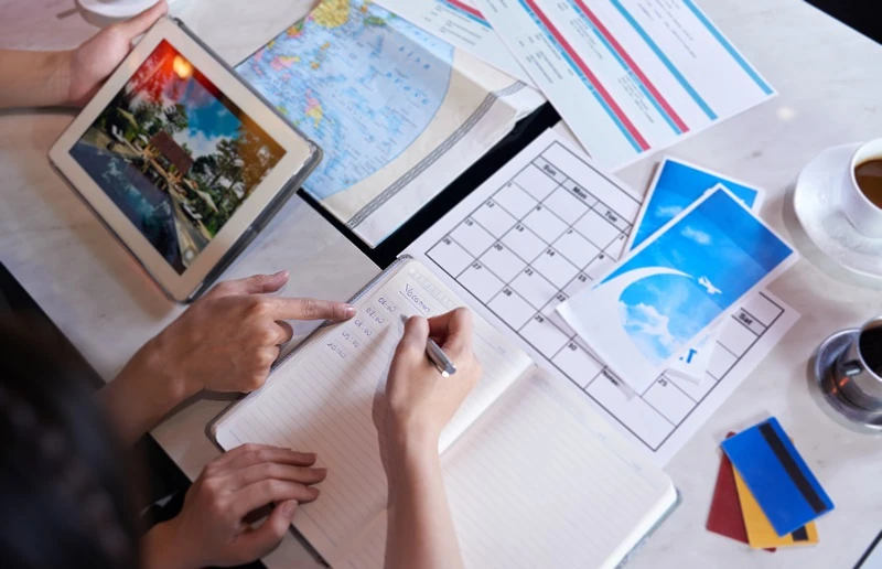 People planning a trip with a map, calendar, and notebook, symbolizing long-tail keyword mapping and travel content planning.